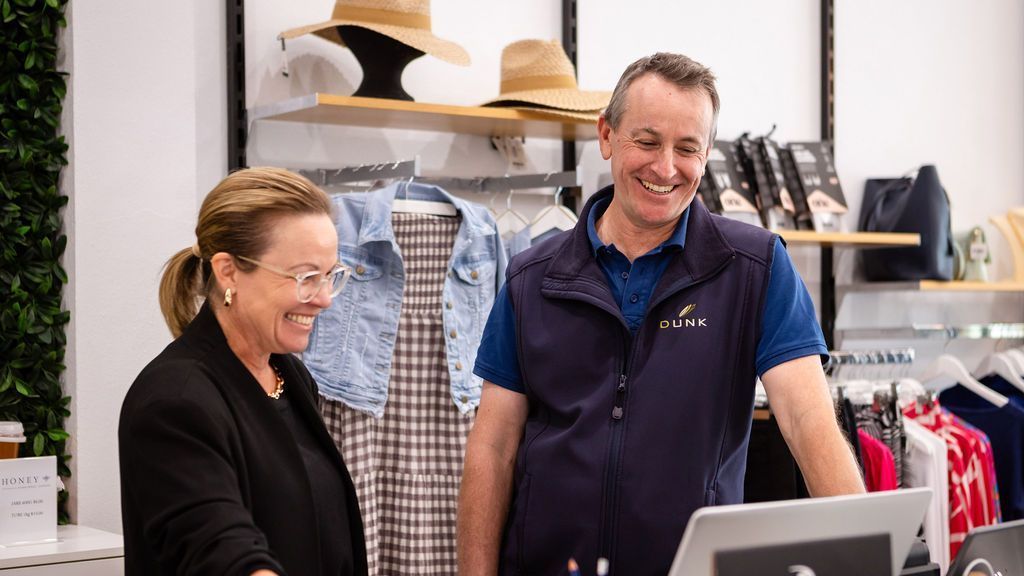 A man and a woman are standing next to each other in a clothing store.