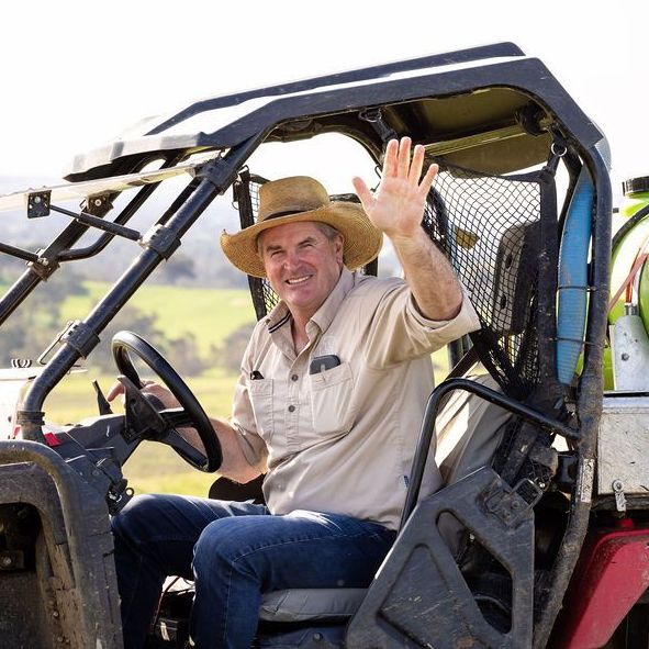 A man wearing a cowboy hat is sitting in a vehicle and waving