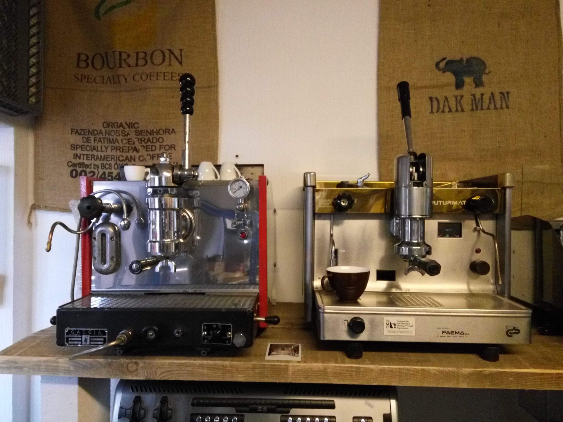 Zwei Kaffeemaschinen stehen auf einer Theke neben einer Tüte mit der Aufschrift „Bourbon“
