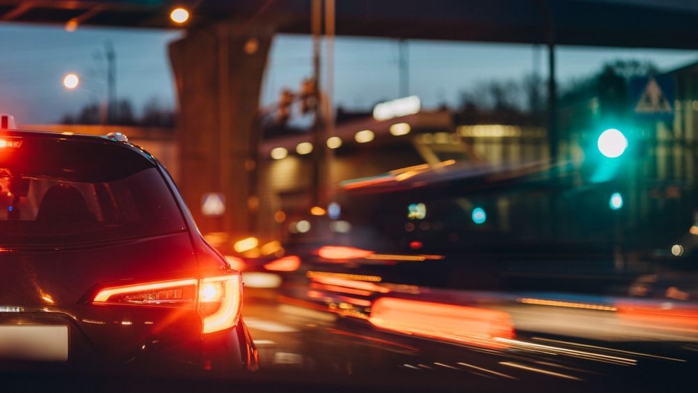 A car is driving down a city street at night.