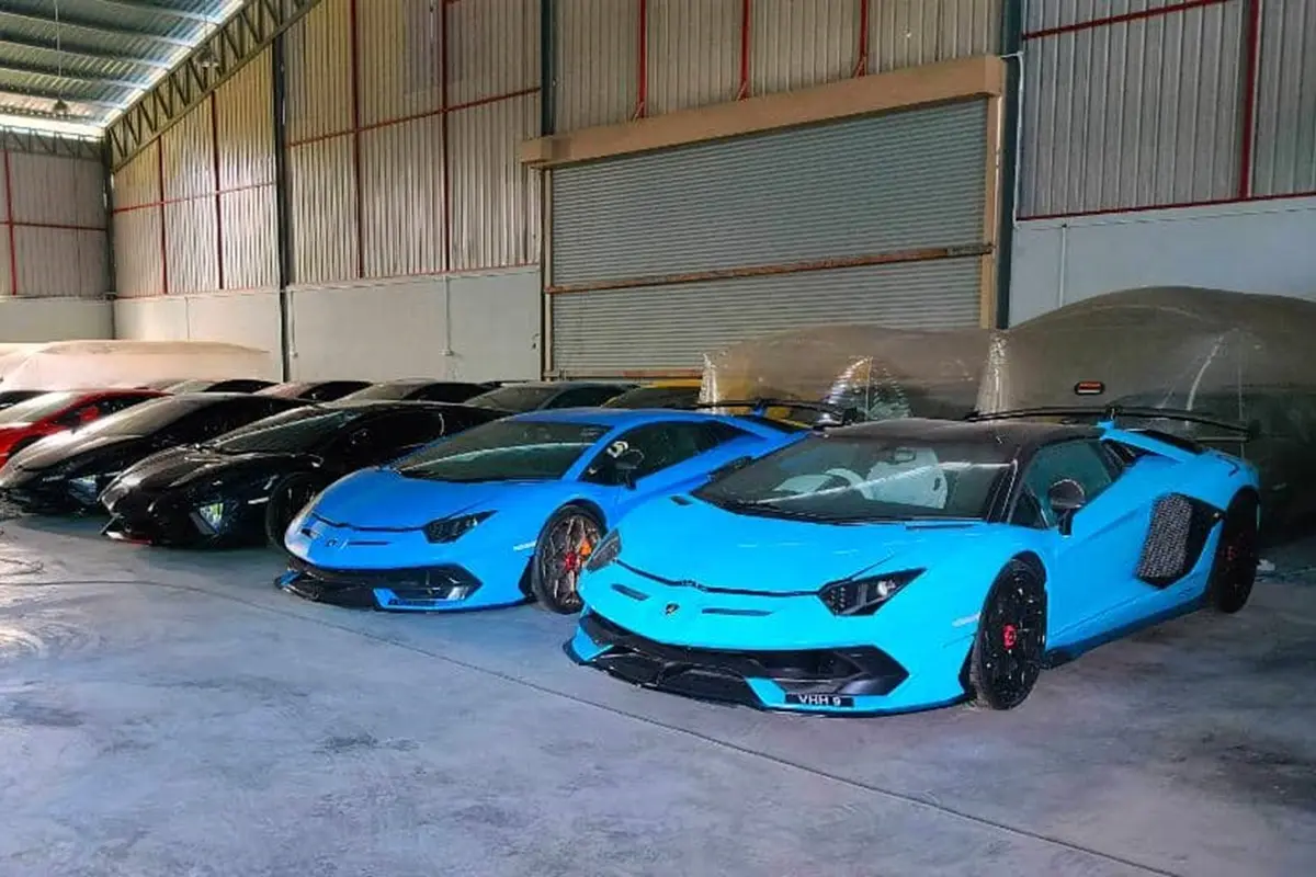 A row of blue sports cars are parked in a warehouse.