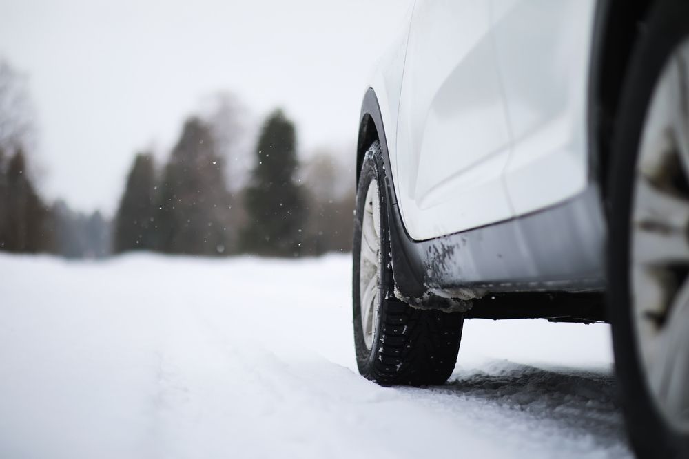 A white car is driving on a snowy road.