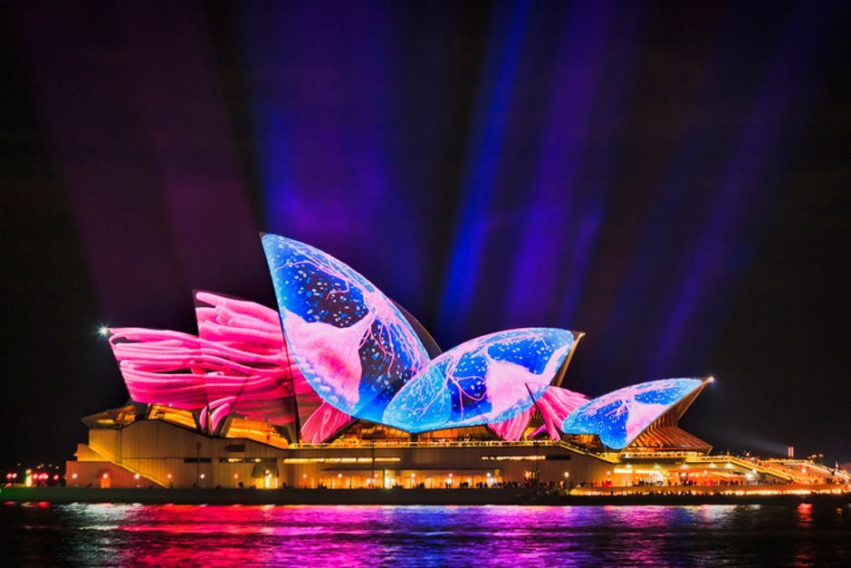The opera house in sydney is lit up at night.