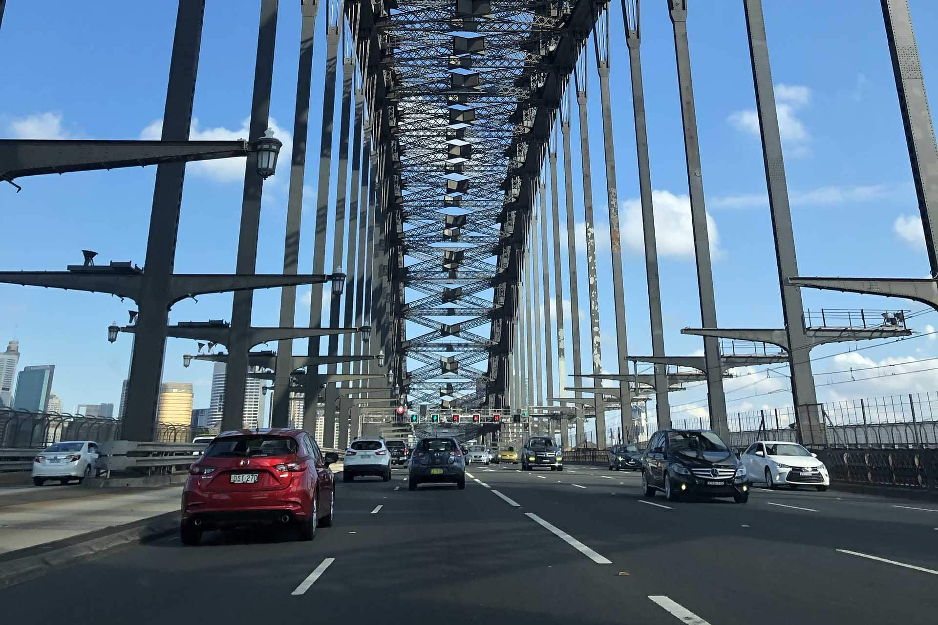 A red car is driving under a bridge
