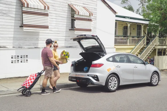 Compact hire car being loaded with bags for a local Brisbane road trip, showing practicality