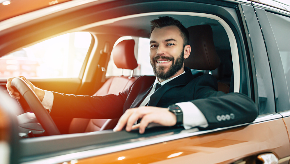 A professional chauffeur in a suit assisting a client with entering a car