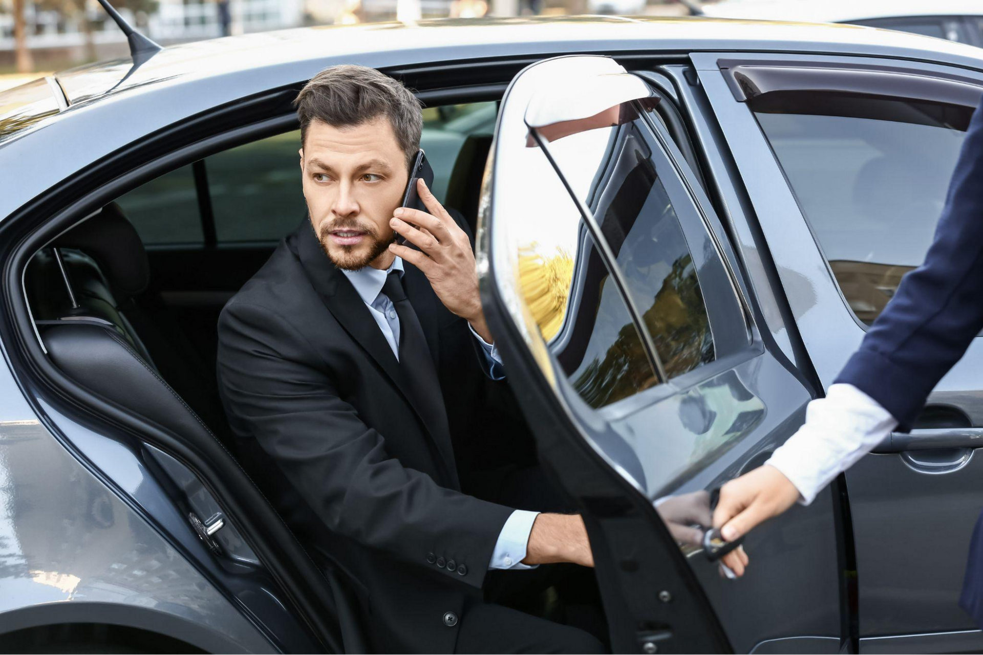 : Professional chauffeur standing by an executive car in Sydney, ready to greet a business client
