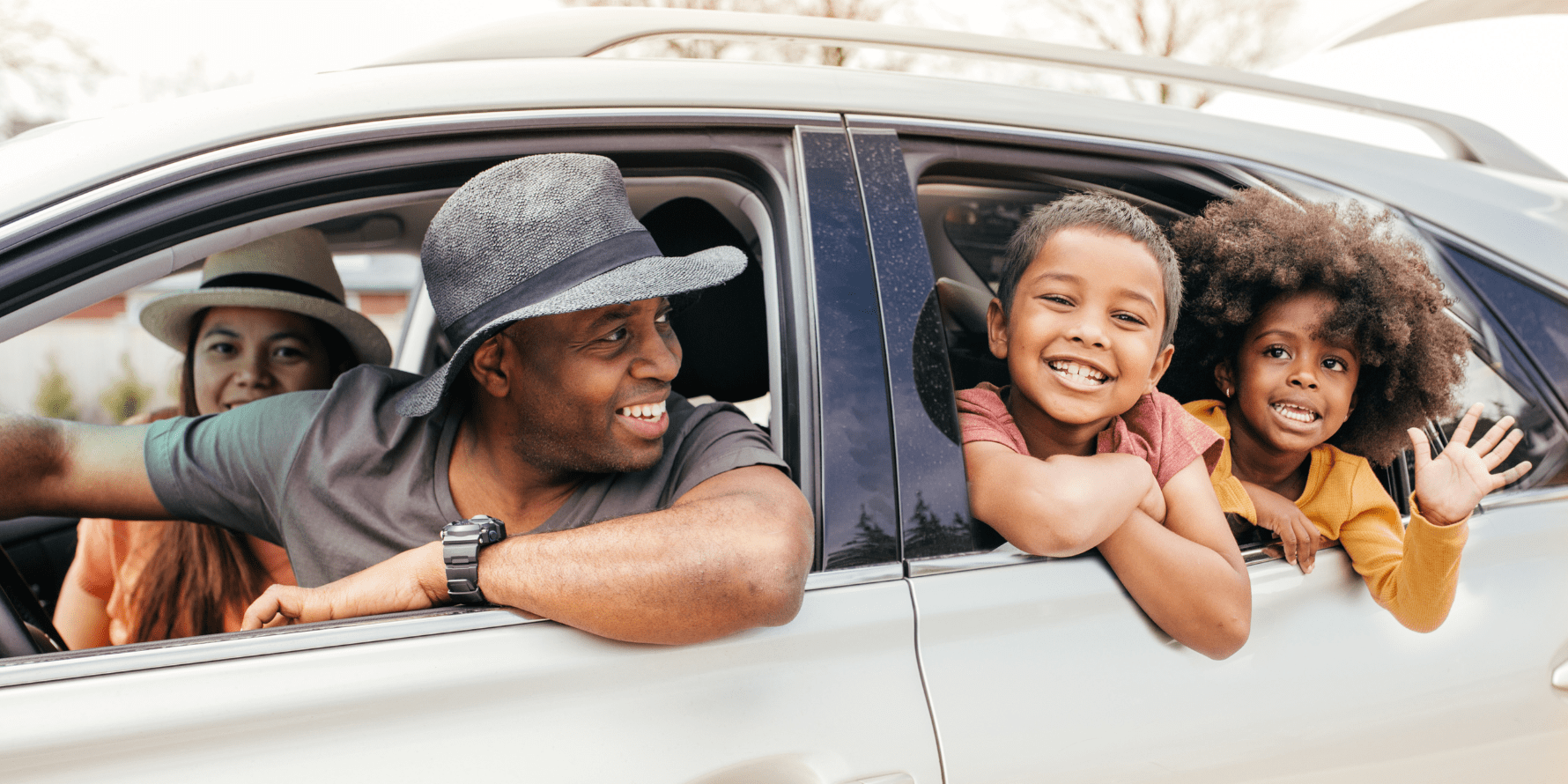 A family is sitting in a car with their heads out the windows.