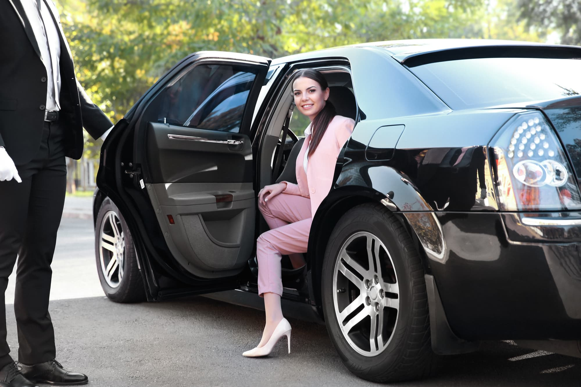 A woman is getting out of a black limousine.