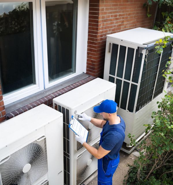 A man is working on an air conditioner outside of a building.
