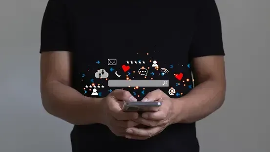 A man in a black shirt is holding a cell phone in his hands.