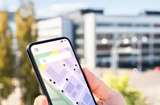 A person is holding a cell phone with a map on the screen.