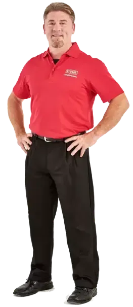 A man in a red shirt and black pants is standing with his hands on his hips.