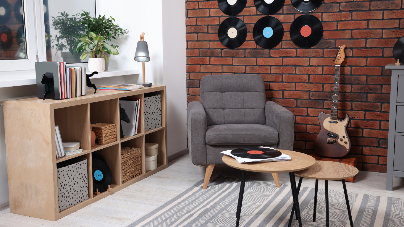 Cozy room with gray armchair, wooden coffee table, and brick wall decorated with vinyl records.