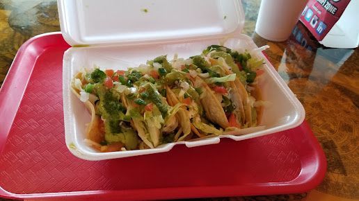 A styrofoam container filled with tacos is on a red tray.