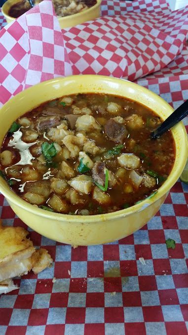 A bowl of soup is sitting on a checkered table cloth.