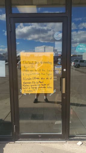 A person is standing in front of a glass door with a sign taped to it.