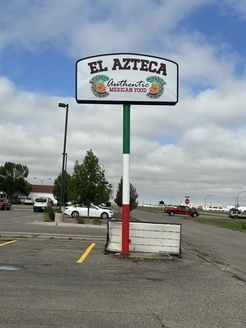 A sign for el azteca is in a parking lot