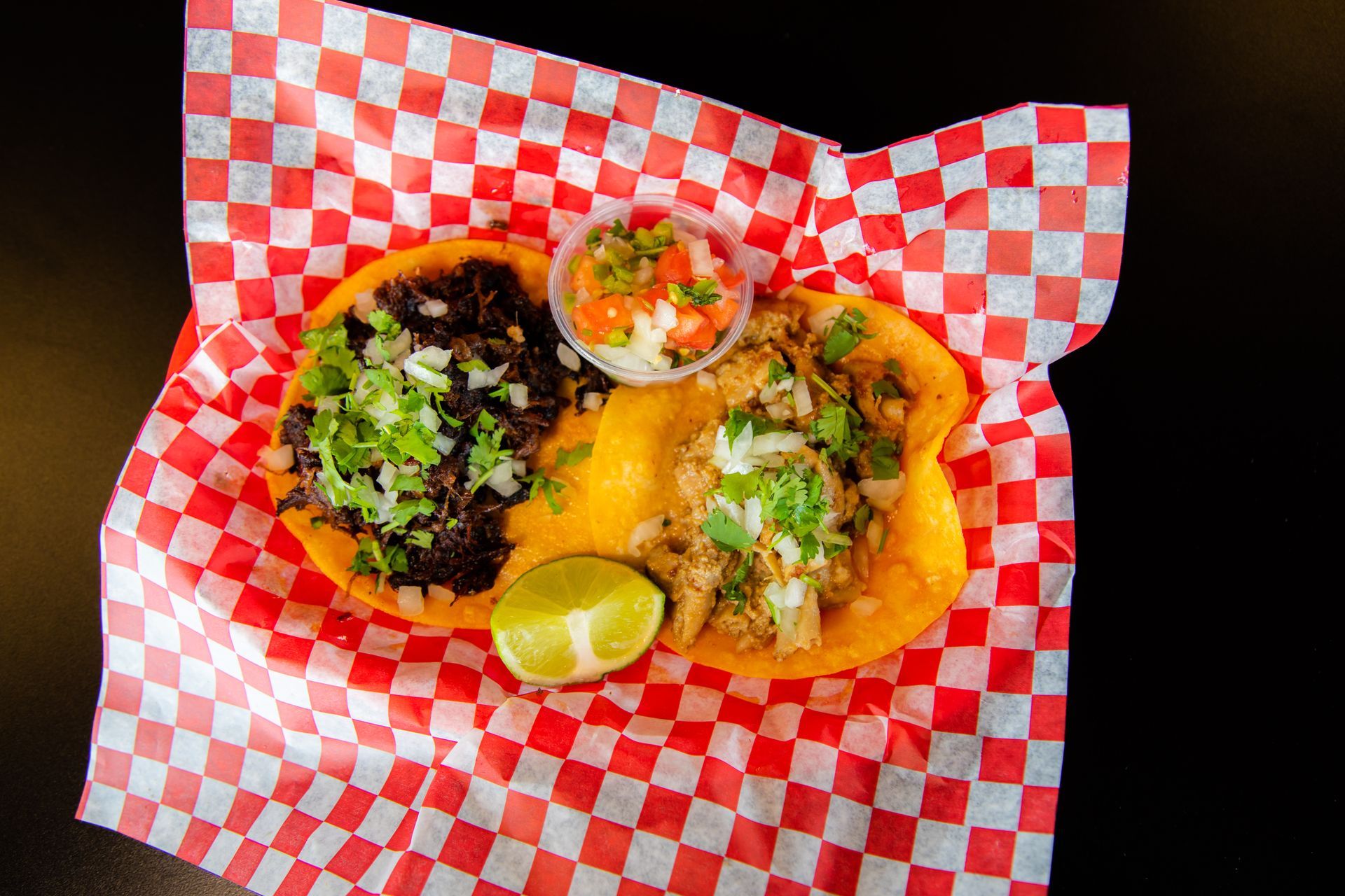 A close up of a taco on a checkered paper on a table.