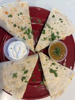 A red plate topped with quesadillas , sour cream and salsa.