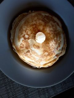 A stack of pancakes with syrup and butter on a plate.