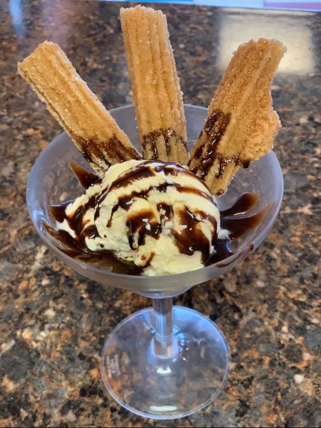 Churros and ice cream in a martini glass on a table