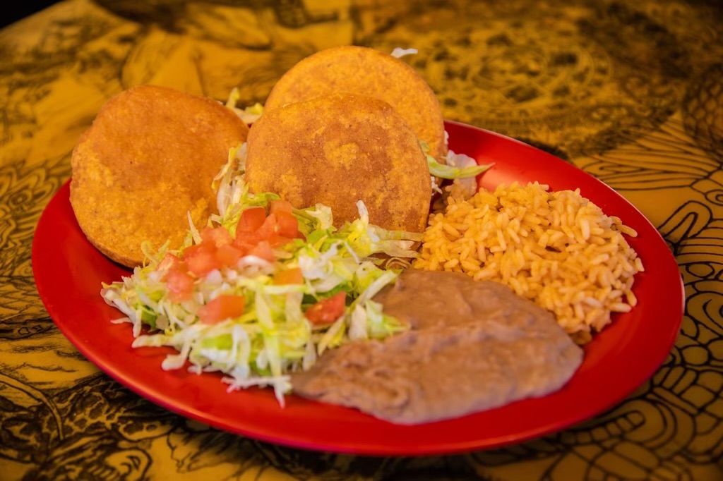 A red plate topped with rice , beans , and tortillas on a table.