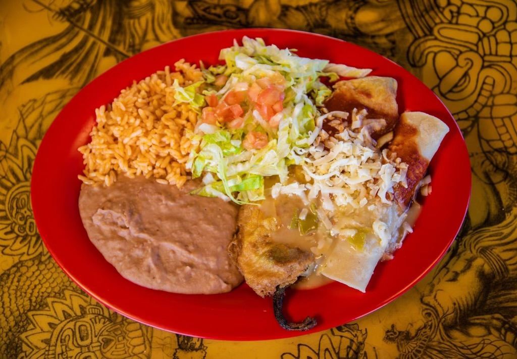 A red plate topped with a variety of mexican food.