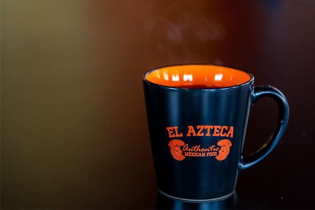 A black and orange coffee mug that says el azteca on it