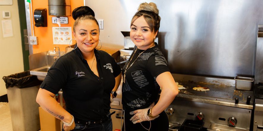 Two women are standing next to each other in a kitchen.