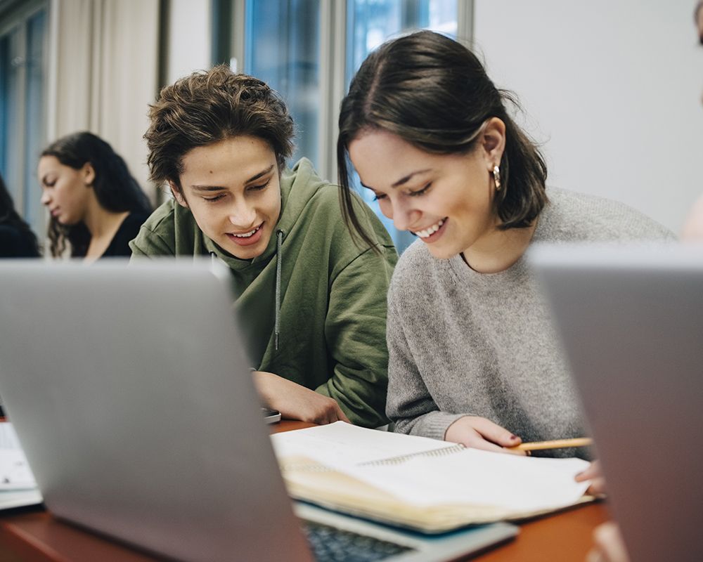 un ragazzo e una ragazza sono seduti davanti a un computer portatile