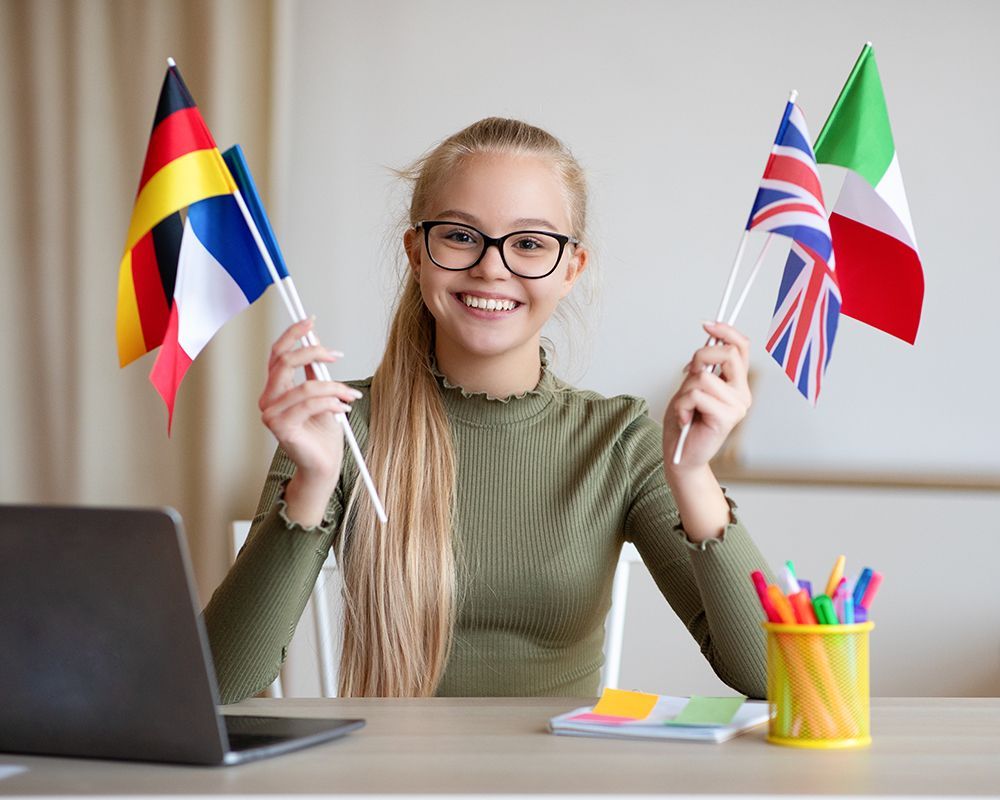 una ragazza sorride mentre tiene in mano le bandiere di diversi paesi