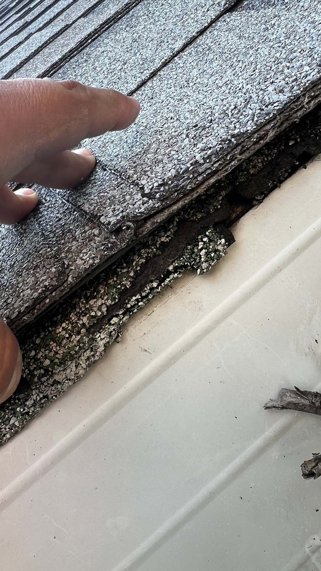 A person is holding a piece of shingles on a roof