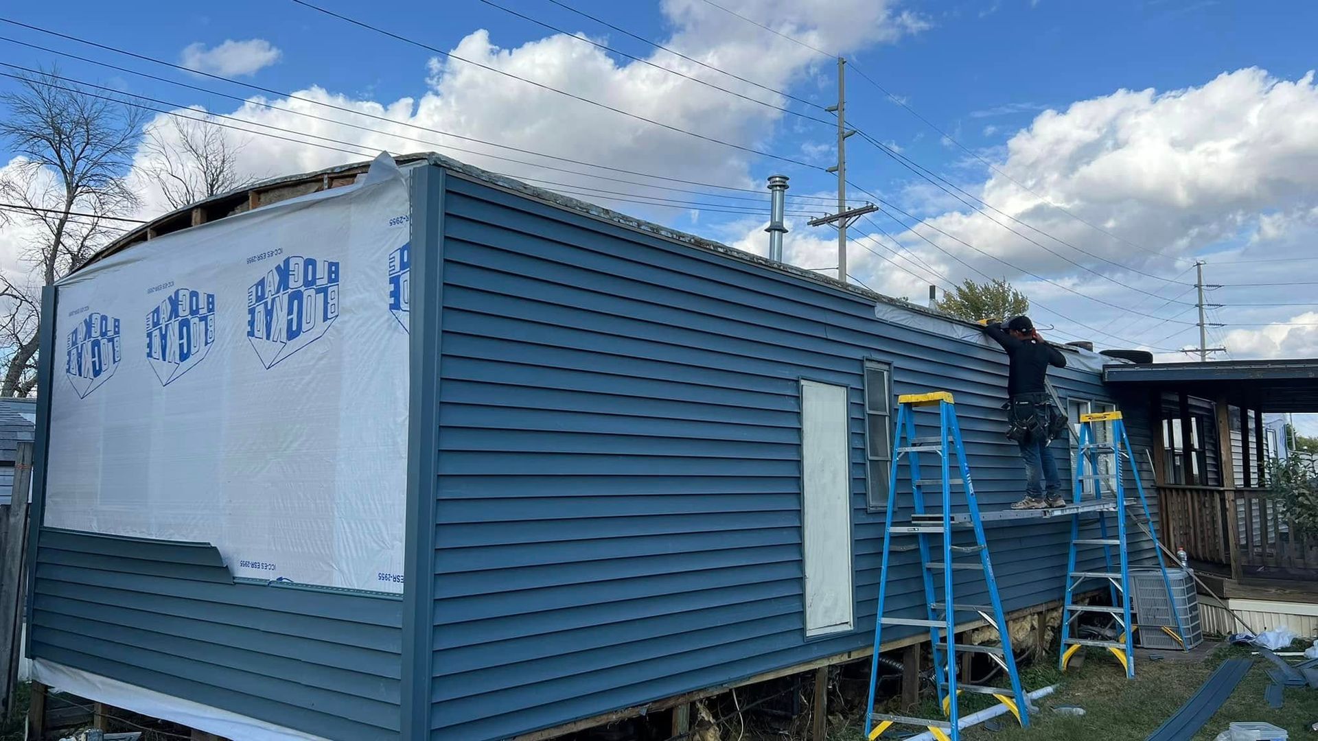A man is standing on a ladder on the side of a house