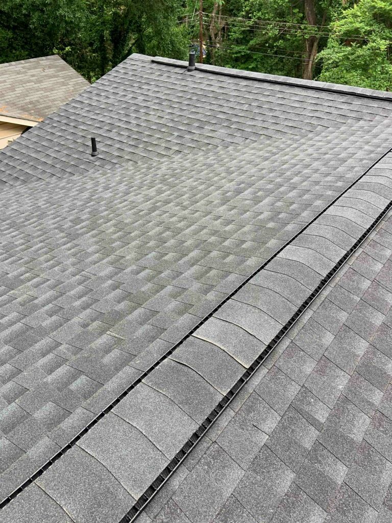 A roof with a lot of shingles on it and trees in the background.