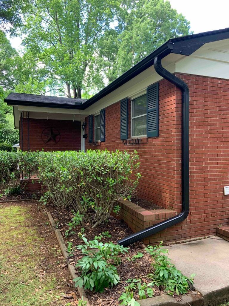 A brick house with a black gutter on the side of it.