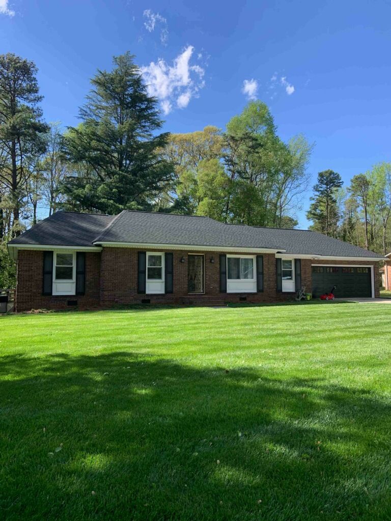 A large brick house with a lush green lawn in front of it.