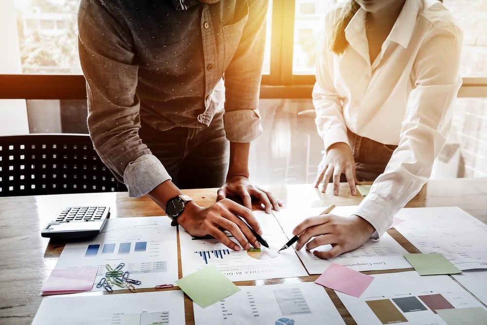 A Man and a Woman Are Looking at Papers on a Table — D&T Accounting & Bookkeeping In Erina, NSW