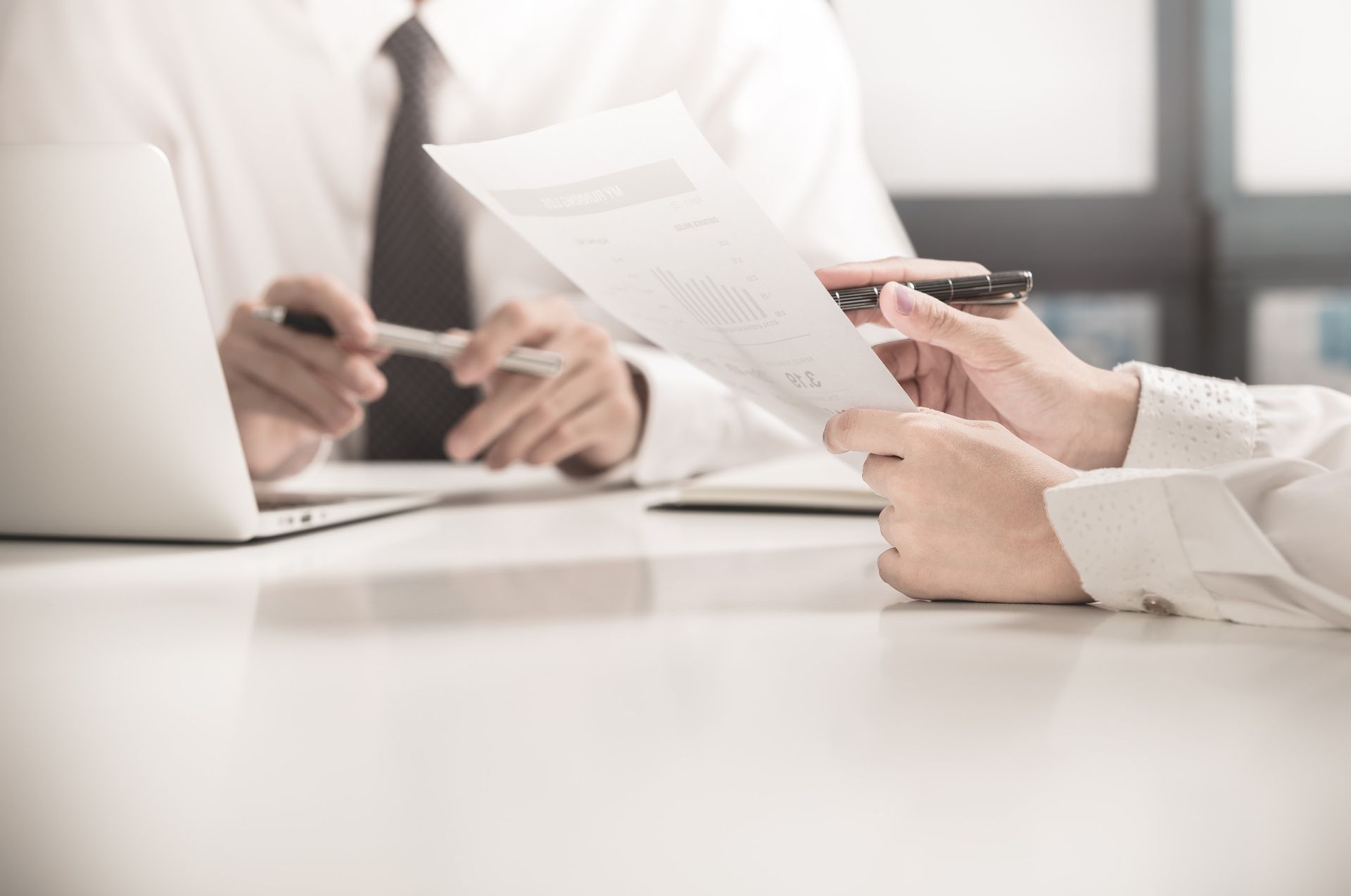 A group of people are sitting at a table looking at a laptop.
