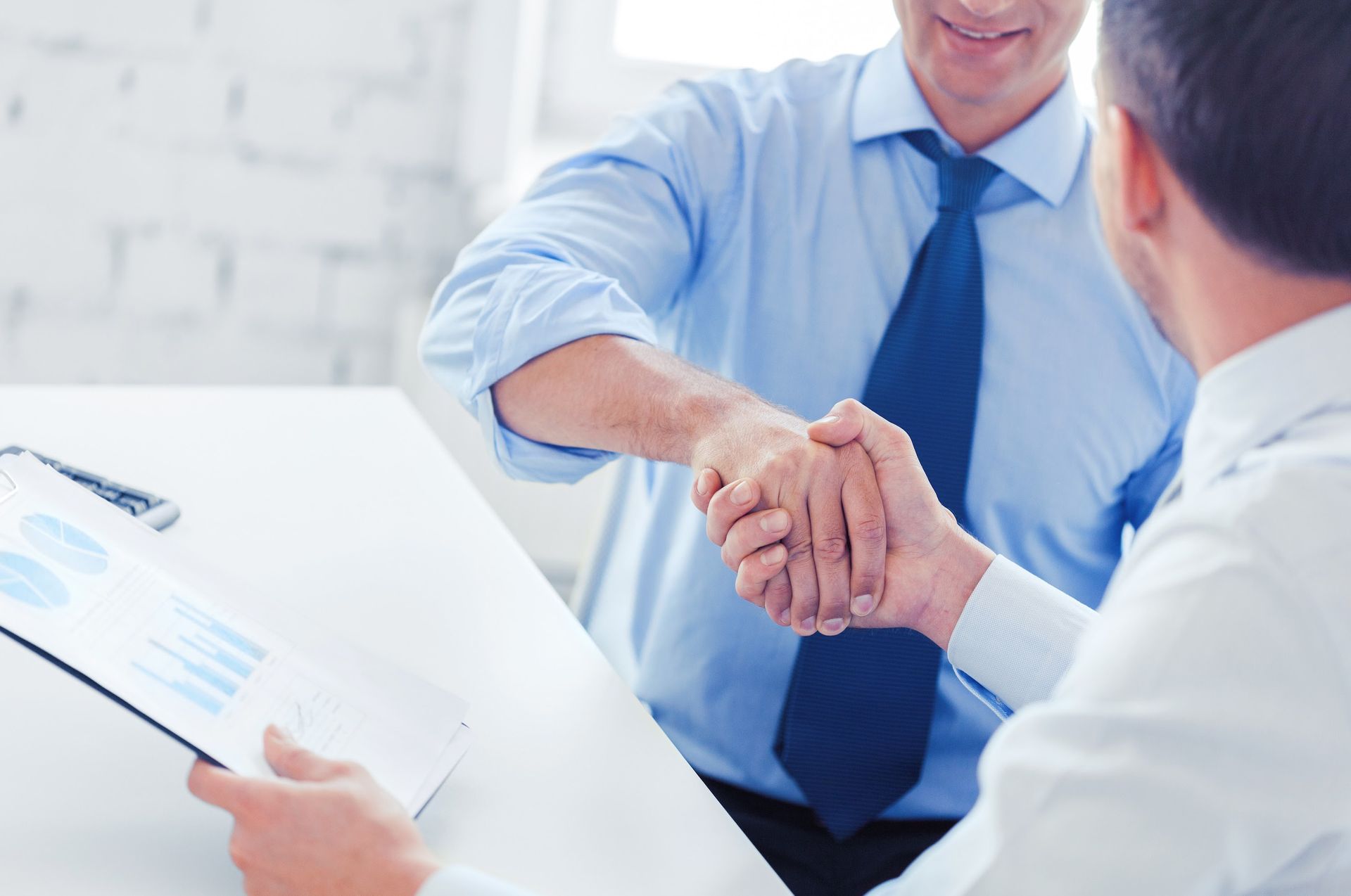 A man in a suit and tie is shaking hands with another man.