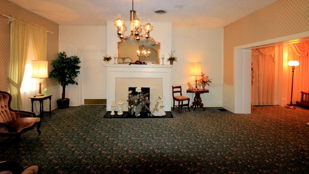 A living room with a fireplace and a chandelier Foster-Toler-Curry Funeral Home Greensburg, KY