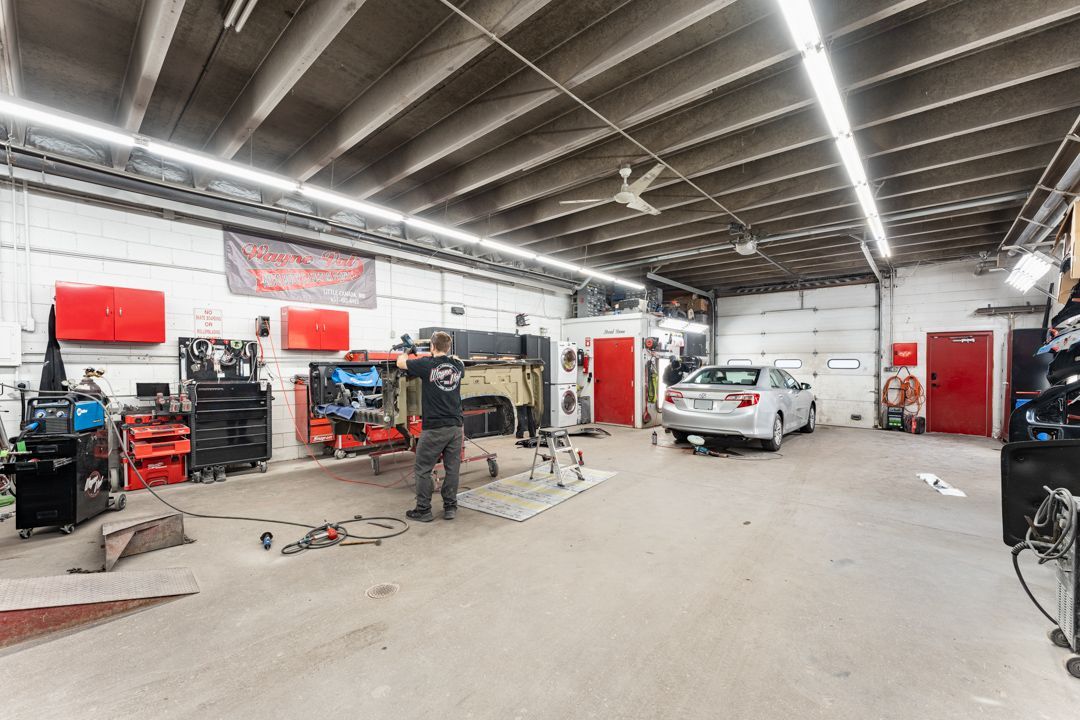 A mechanic working on a car inside a well-lit auto repair shop with tools and equipment.
