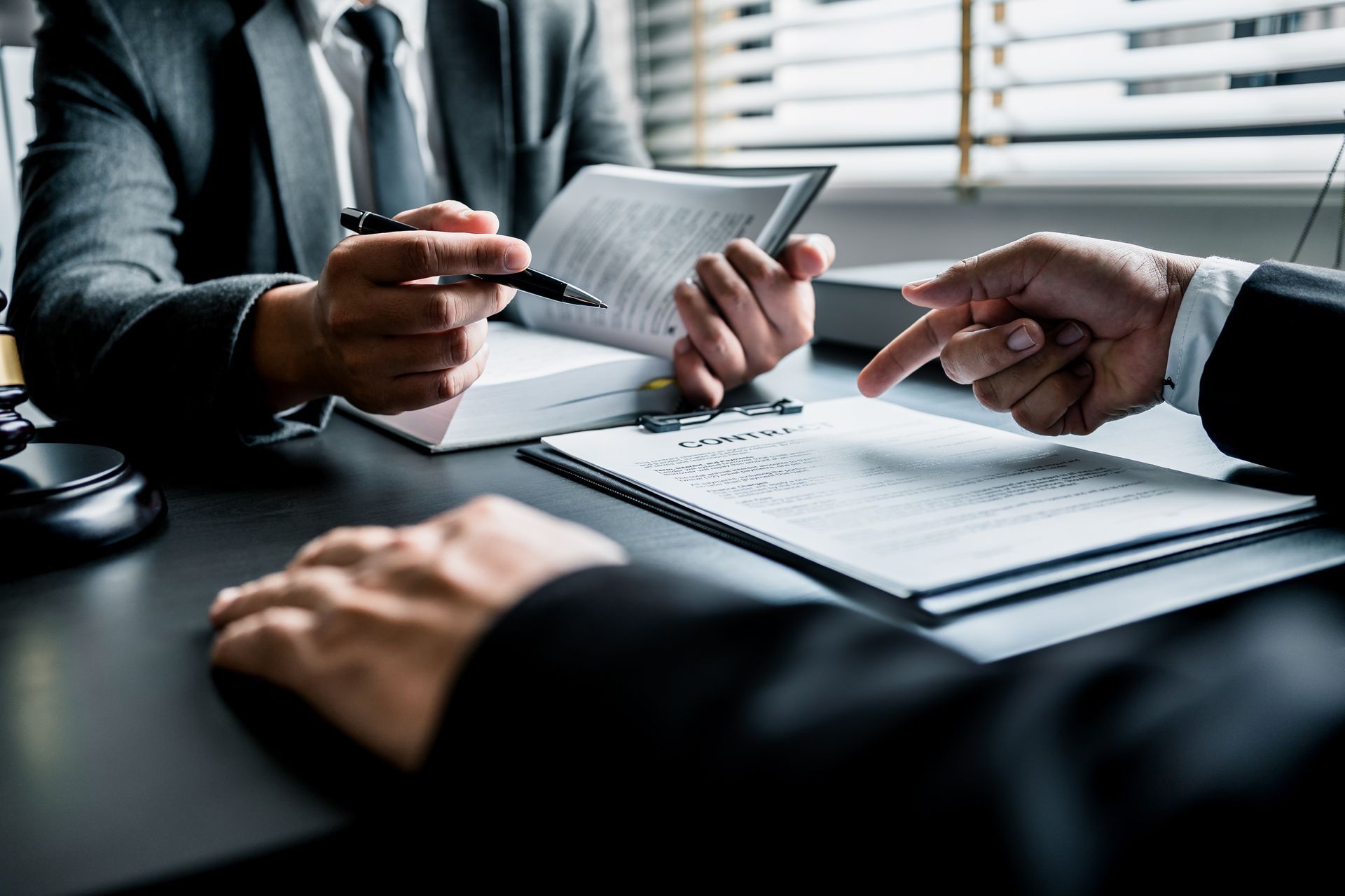 Hands discussing paperwork with a tablet and pen over a desk in a business meeting