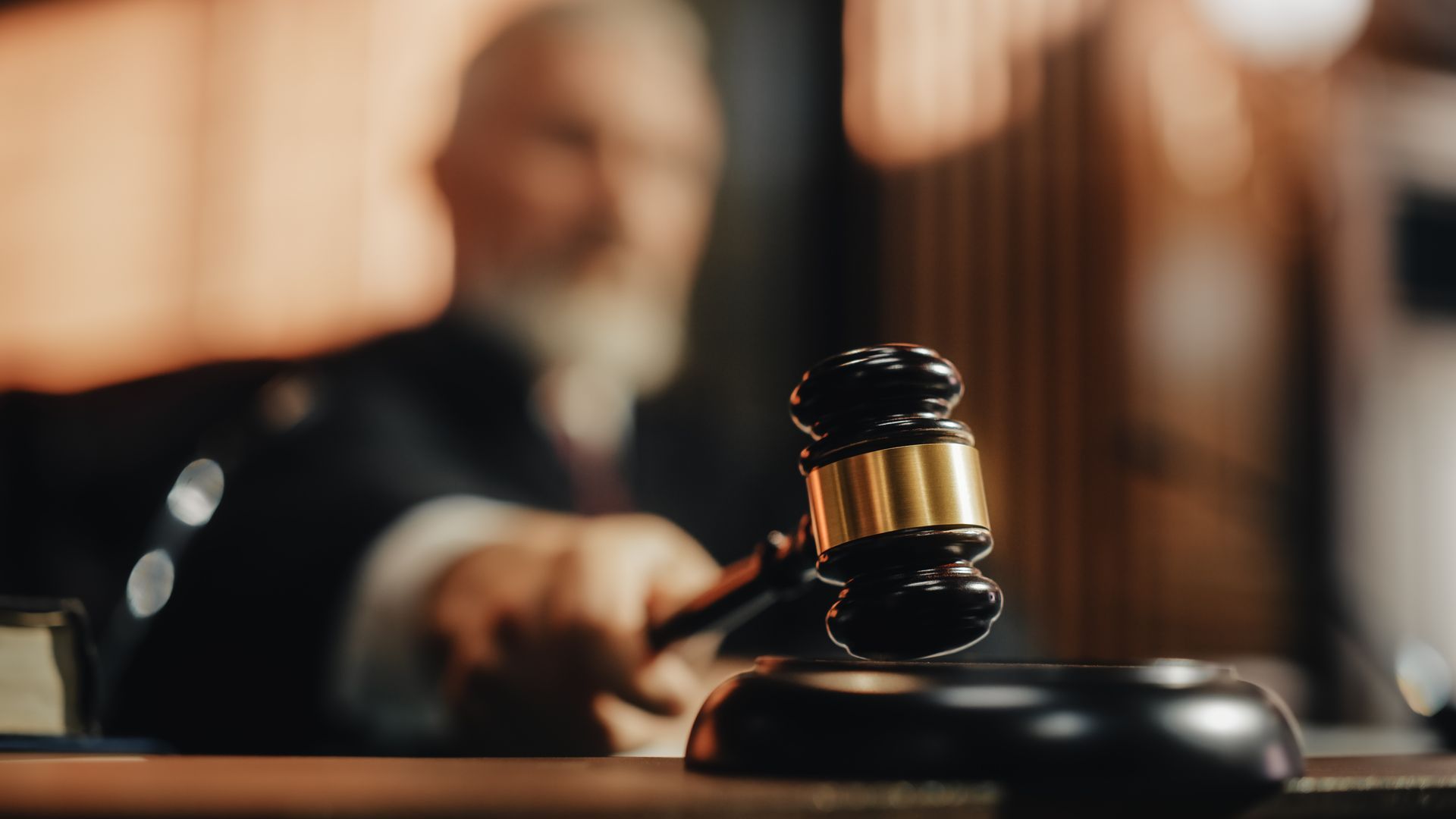Judge holding gavel in courtroom, ready to strike the sound block