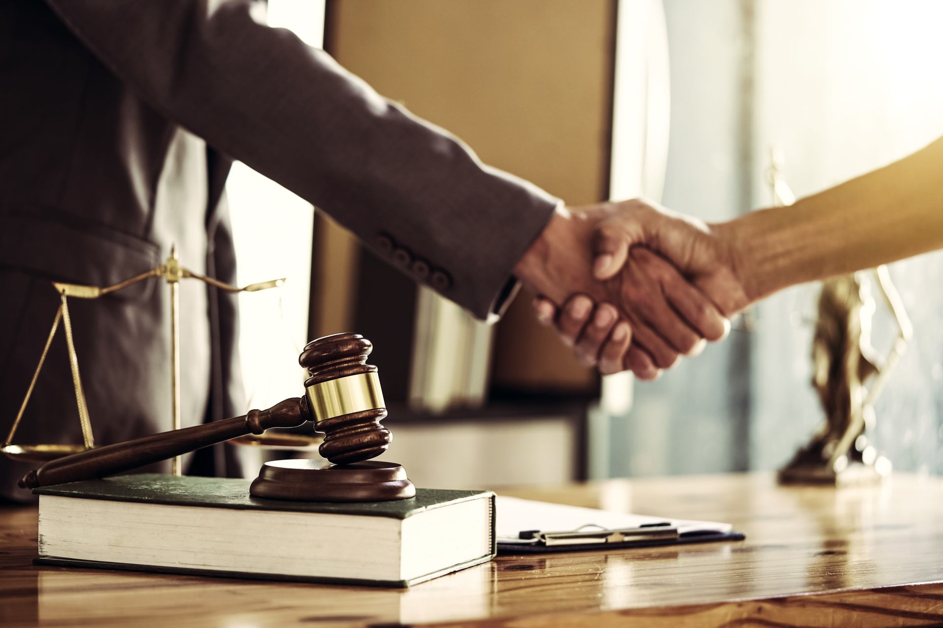 Lawyer shaking hands beside gavel and legal books in a courtroom