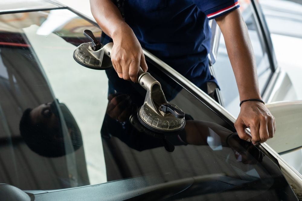 A man is installing a windshield on a car.