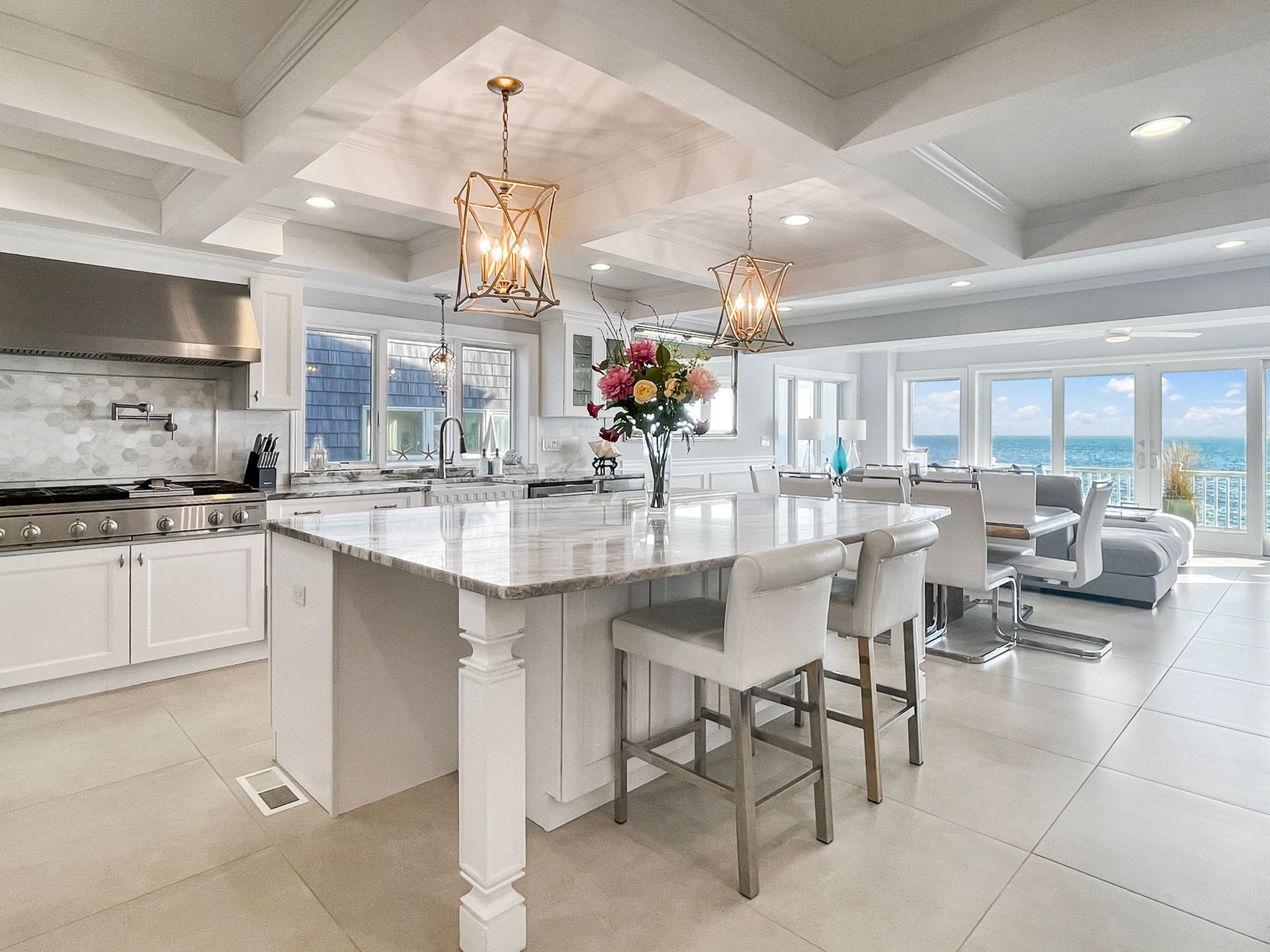 A multi-story home with light shingles, a front porch, and a white fence along a sunny, grassy front yard.