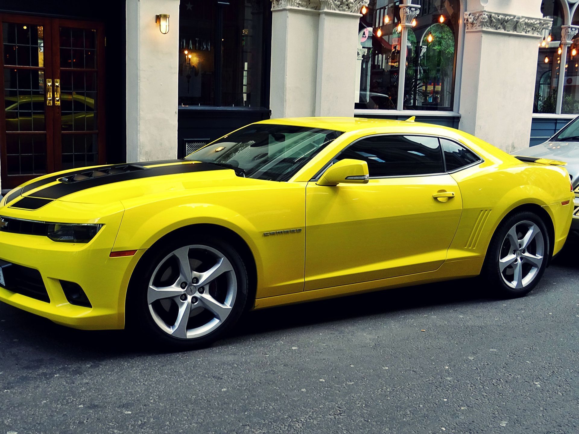 A yellow car is parked in front of a building