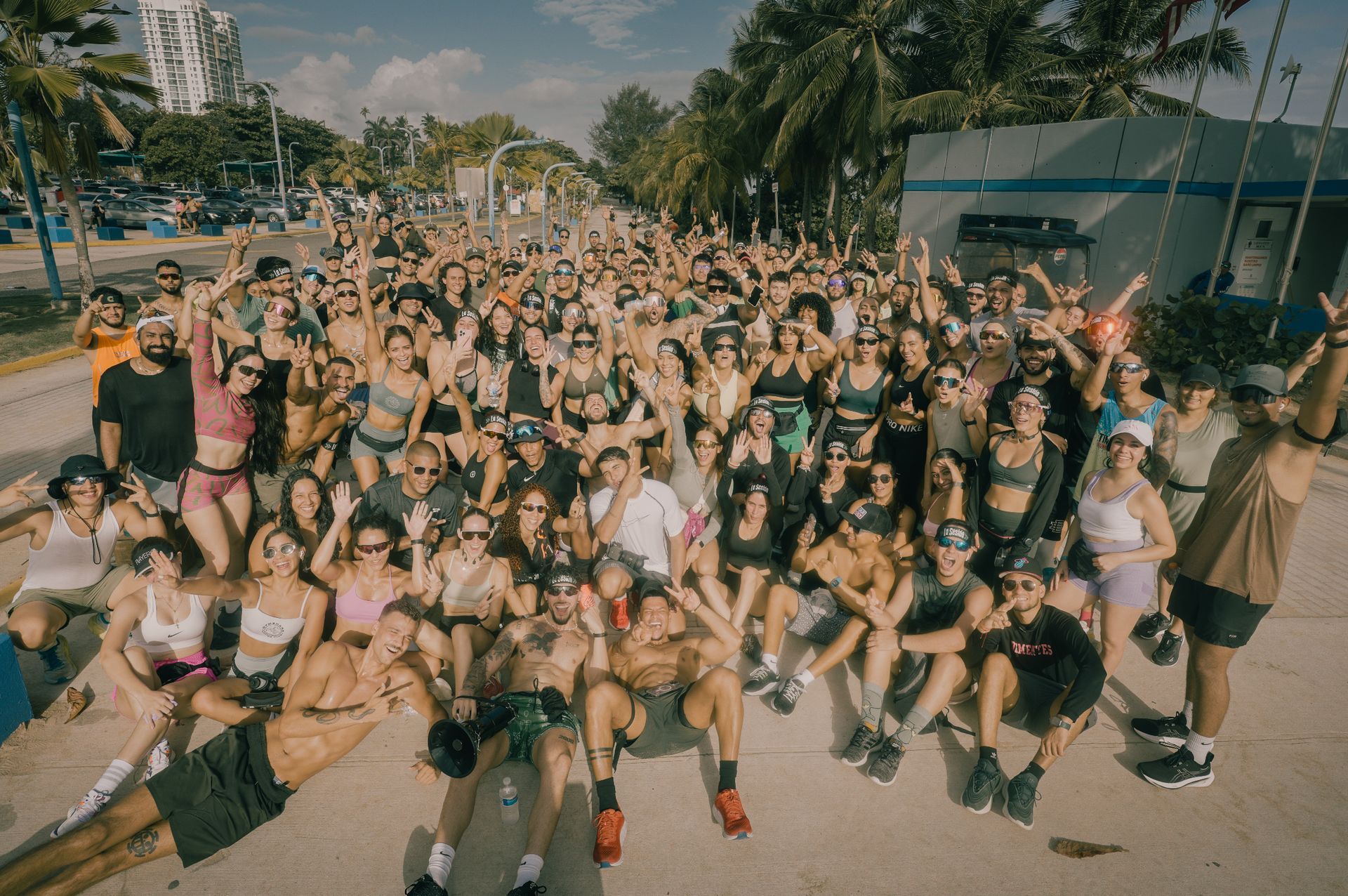 Large group of people posing outdoors; sunny day. Some are sitting, many are smiling and waving. Diego Ramirez, La Sesión