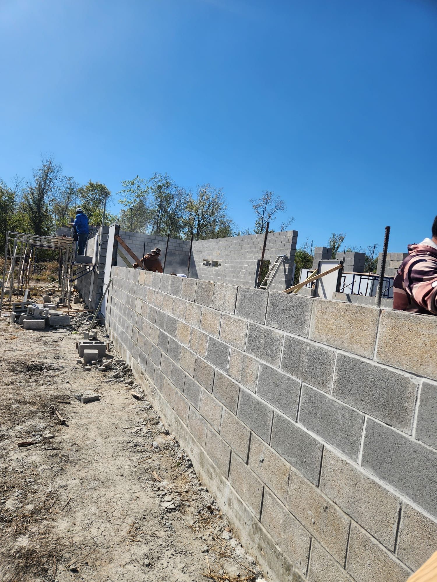 Construction site with concrete block walls under construction, blue sky.